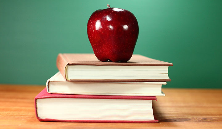 Stacked books with red apple on top